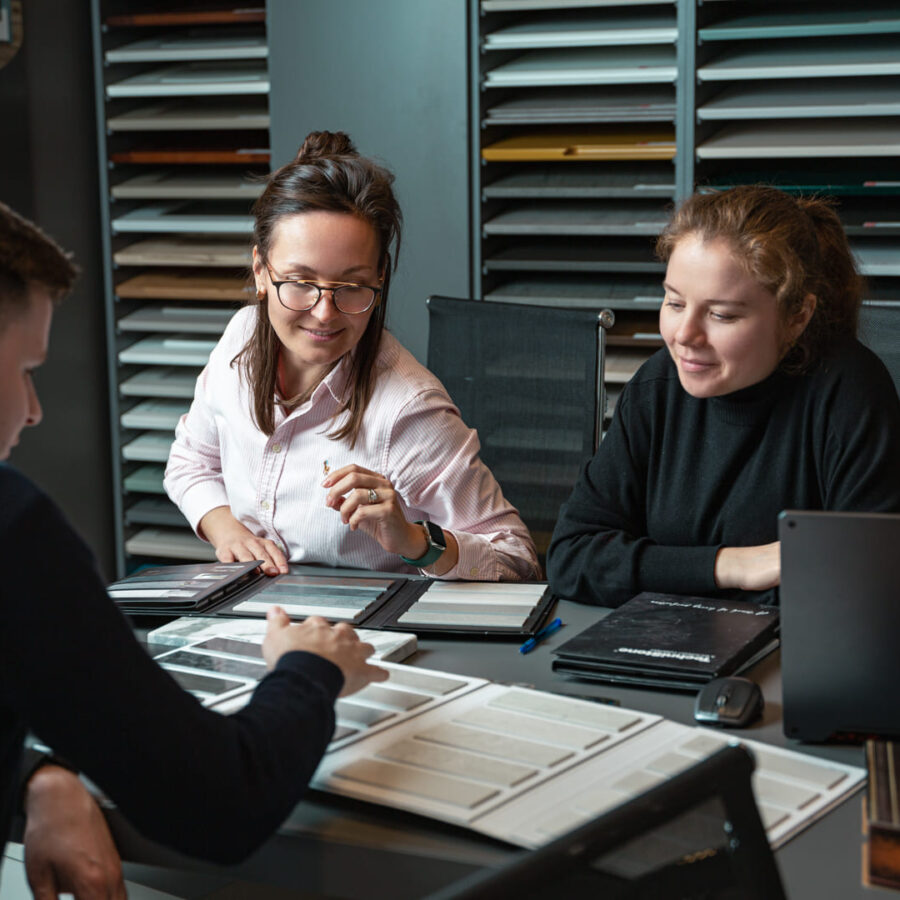 Professional business team meeting in a showroom, reviewing and discussing product samples together.