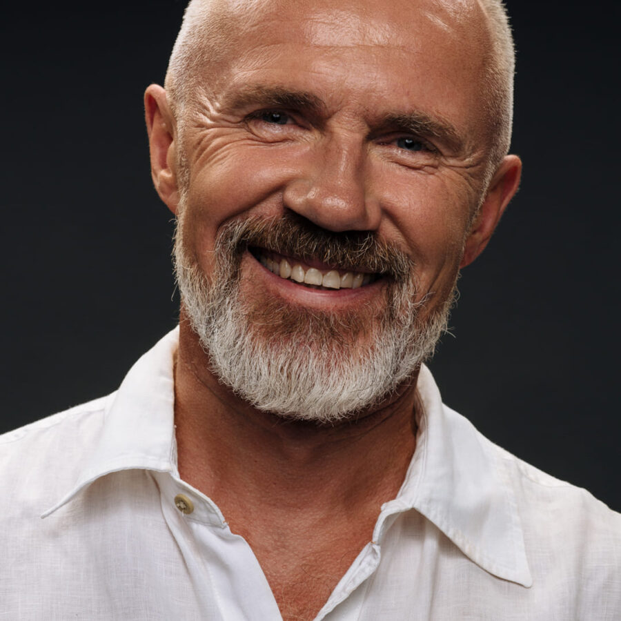 Confident professional in a white shirt, posing for a corporate headshot.