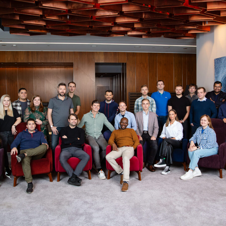 Group photo of a professional team gathered in a modern office lounge, showcasing a diverse and collaborative work environment.