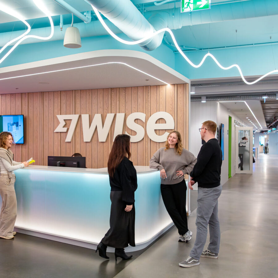 Neli inimest vestlevad kontoris, taustal Wise'i logo - professionaalsed ametiportreed